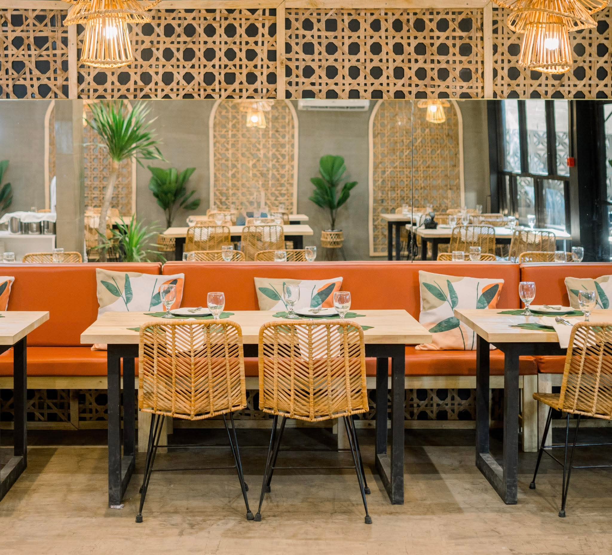Warm Yaelitos dining room with rattan chairs and orange banquette seating
