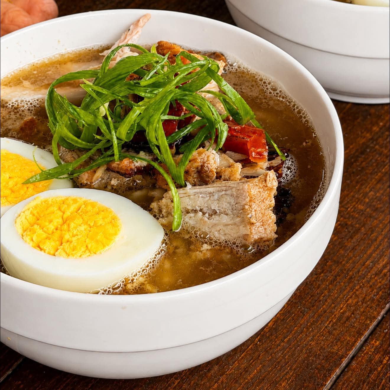 A warm Yaelitos comfort bowl topped with egg, meat, and spring onions