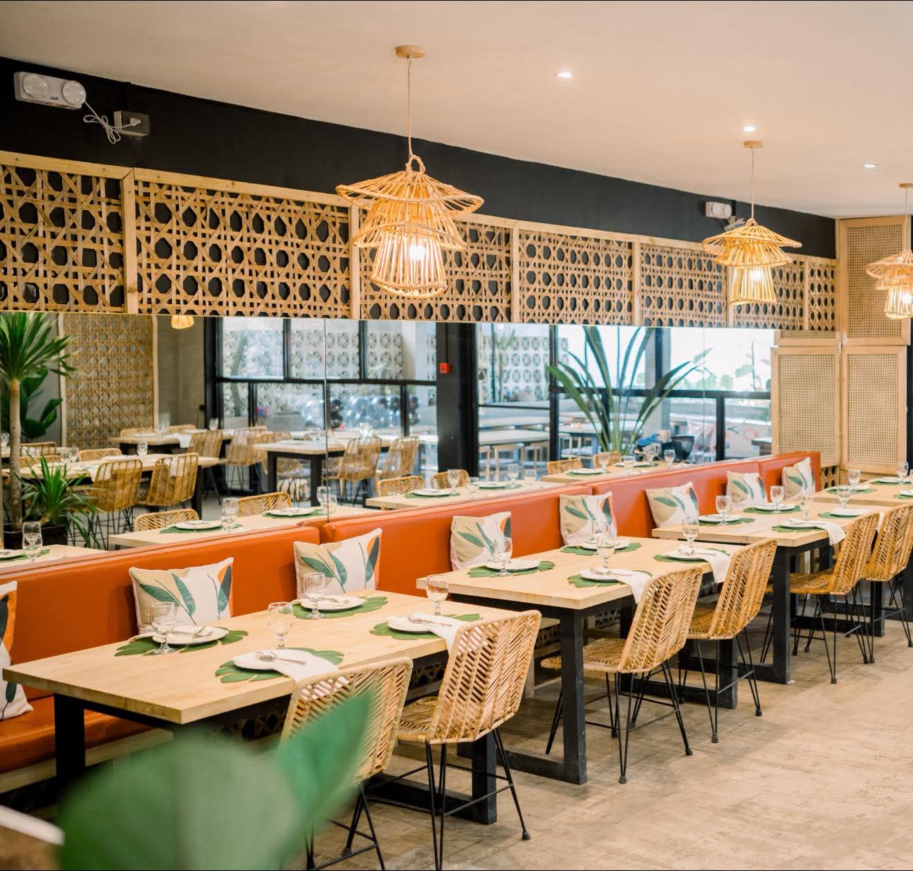 Yaelitos dining room prepared with tables, rattan chairs, mirrors, and warm pendant lights